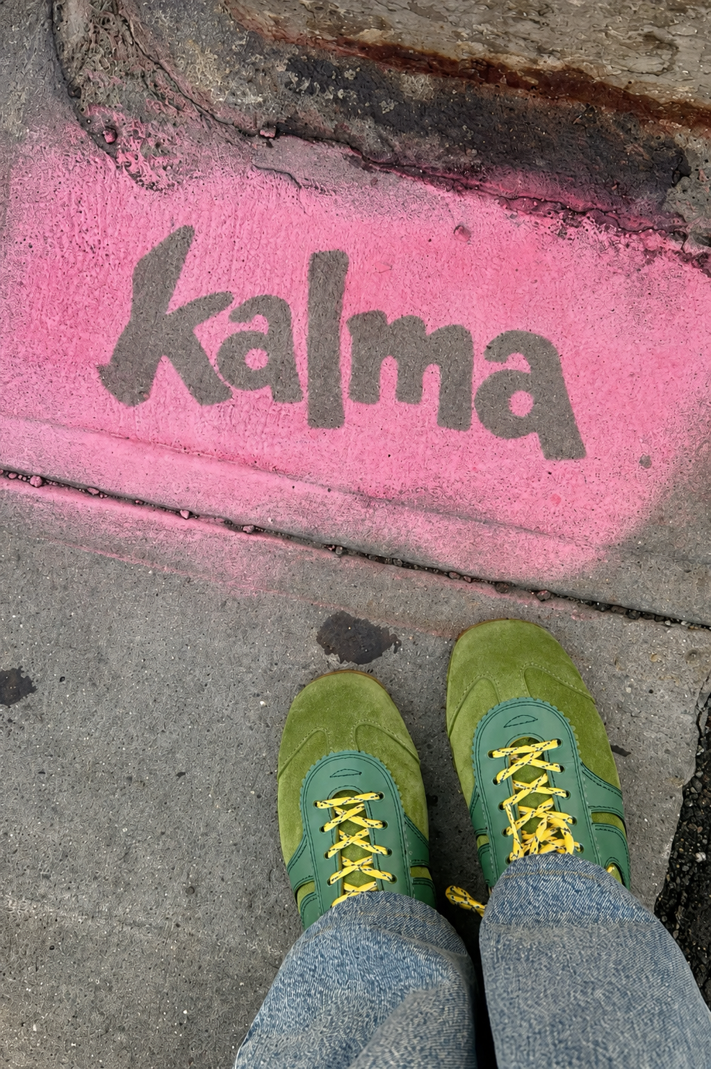 Logo de Kalma pintado en el suelo junto a unas zapatillas verdes