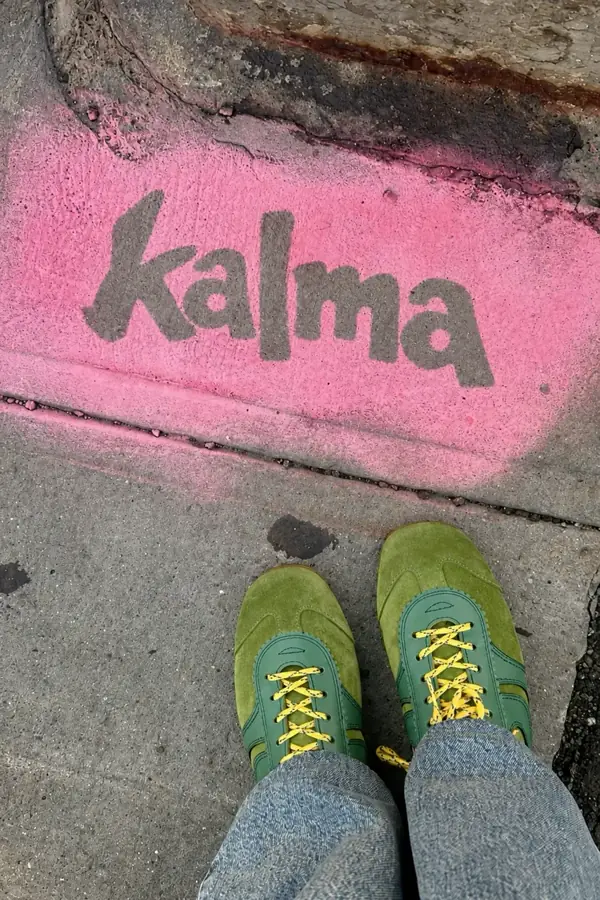 Logo de Kalma pintado en el suelo junto a unas zapatillas verdes
