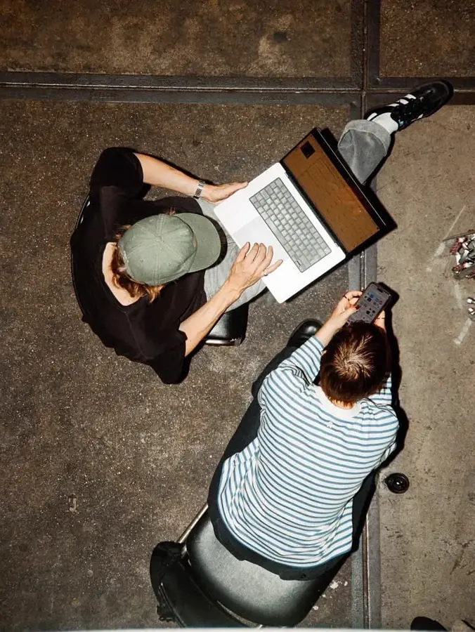 Dos personas trabajando con portátil y móvil, vistas desde arriba
